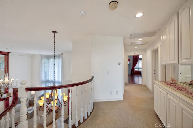 corridor with light colored carpet and a chandelier