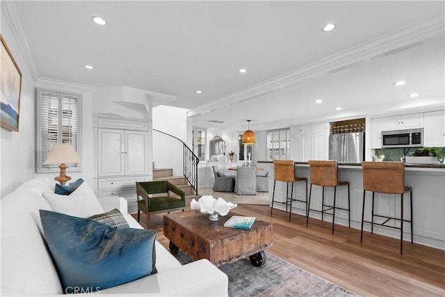 living room with ornamental molding and light hardwood / wood-style flooring