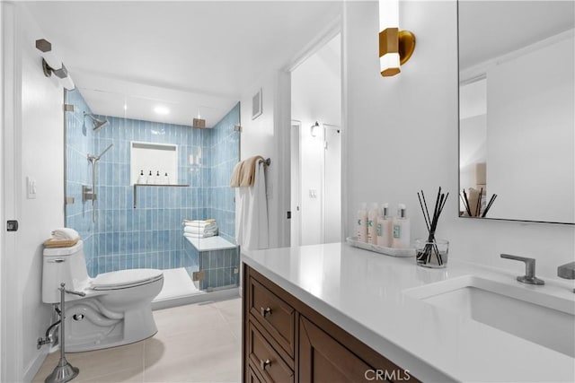 bathroom with tile patterned floors, toilet, a tile shower, and vanity