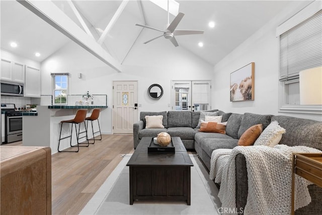 living room with beam ceiling, light hardwood / wood-style floors, high vaulted ceiling, and ceiling fan