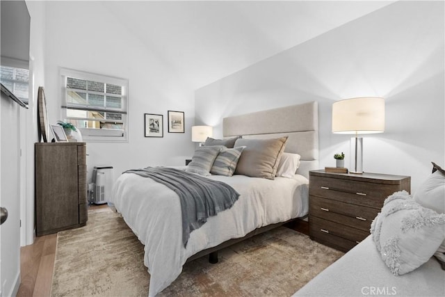 bedroom with light hardwood / wood-style flooring and high vaulted ceiling