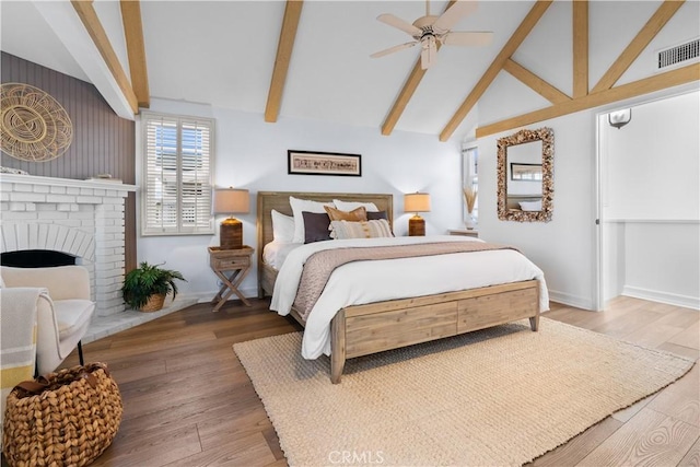 bedroom with high vaulted ceiling, ceiling fan, a fireplace, beam ceiling, and wood-type flooring