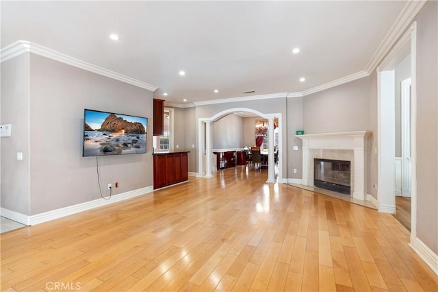 unfurnished living room with ornamental molding, a premium fireplace, and light wood-type flooring