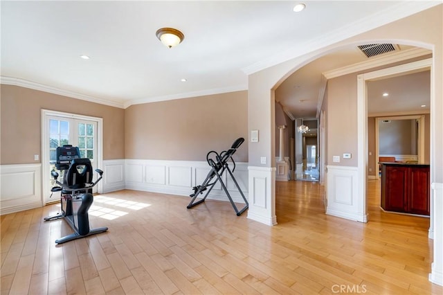 exercise area with light wood-type flooring and crown molding