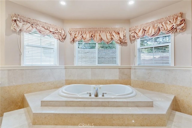 bathroom with a relaxing tiled tub and a healthy amount of sunlight