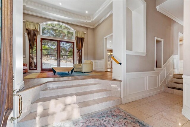 interior space with a raised ceiling, crown molding, and french doors