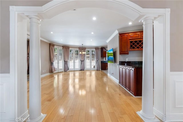 kitchen with ornate columns, crown molding, pendant lighting, and light hardwood / wood-style flooring