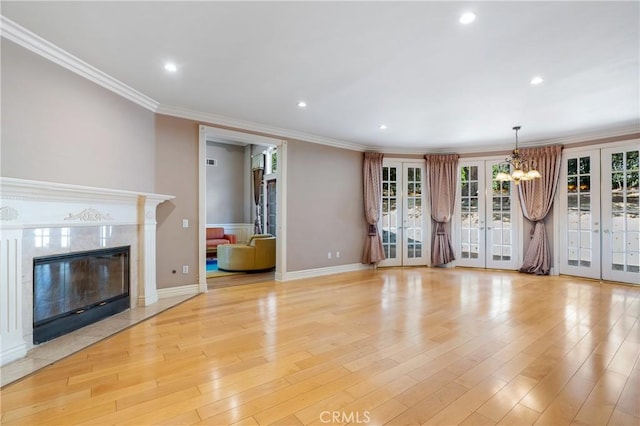 unfurnished living room with a high end fireplace, light hardwood / wood-style flooring, ornamental molding, and french doors