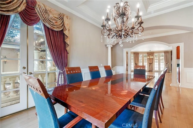 dining room with ornate columns, french doors, a notable chandelier, crown molding, and light hardwood / wood-style floors