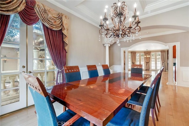 dining area with ornate columns, crown molding, a chandelier, and light hardwood / wood-style flooring