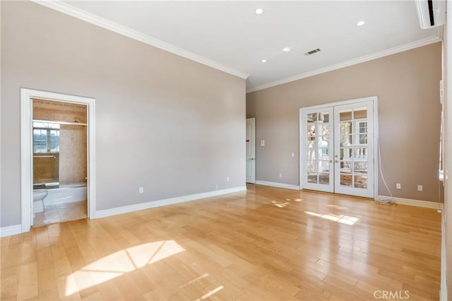 empty room with crown molding, french doors, and light hardwood / wood-style floors