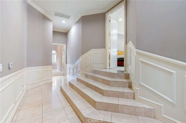 stairway with tile patterned floors and ornamental molding