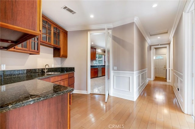 kitchen featuring crown molding, sink, dark stone counters, and light hardwood / wood-style flooring