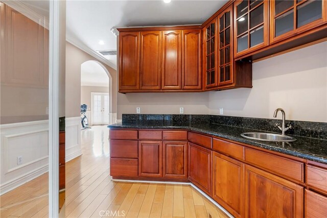 kitchen featuring dark stone countertops, sink, light hardwood / wood-style floors, and ornamental molding