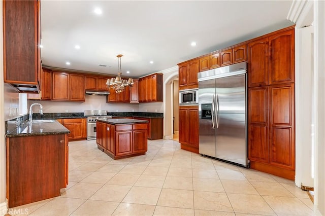 kitchen featuring sink, built in appliances, decorative light fixtures, dark stone countertops, and a center island