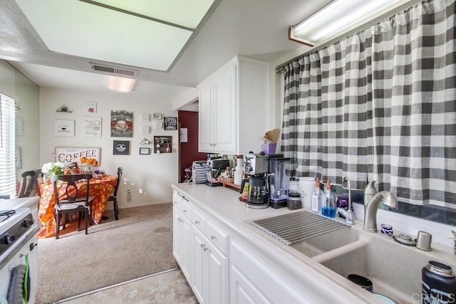 kitchen with sink, white cabinetry, light carpet, and electric stove