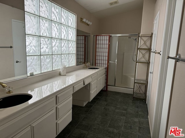 bathroom with a shower with door, vanity, and a healthy amount of sunlight