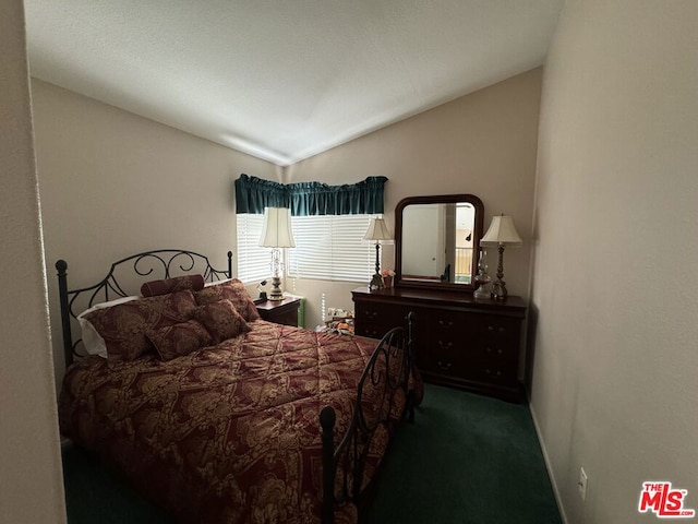 bedroom featuring lofted ceiling and dark carpet