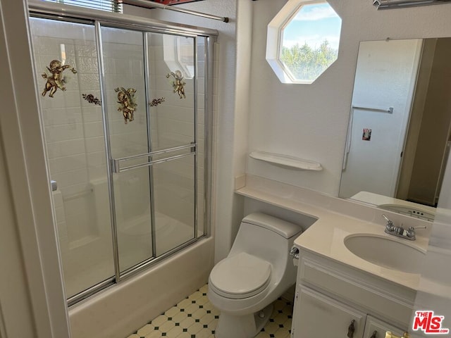 full bathroom featuring vanity, bath / shower combo with glass door, and toilet