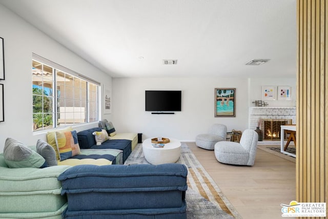 living room with a brick fireplace and light hardwood / wood-style floors