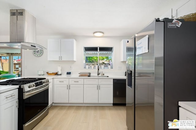 kitchen with sink, island range hood, white cabinets, and appliances with stainless steel finishes