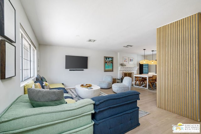 living room featuring a brick fireplace and light wood-type flooring