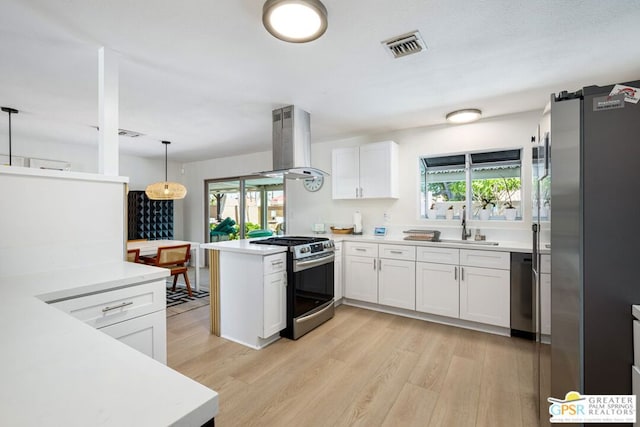 kitchen with pendant lighting, appliances with stainless steel finishes, white cabinetry, island exhaust hood, and kitchen peninsula