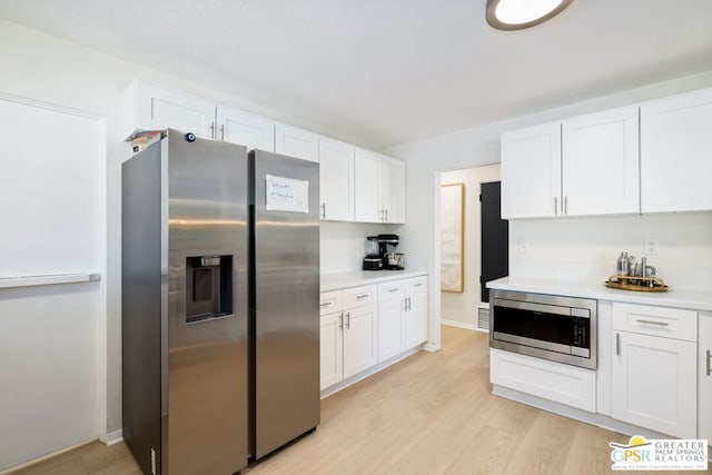 kitchen with white cabinetry, appliances with stainless steel finishes, and light wood-type flooring