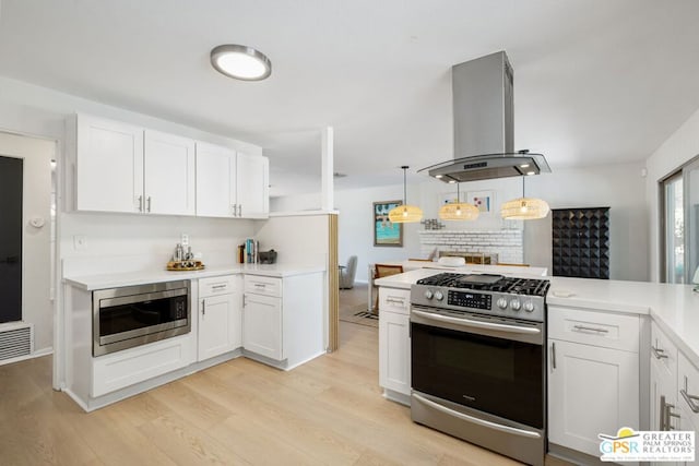 kitchen featuring hanging light fixtures, light wood-type flooring, appliances with stainless steel finishes, island exhaust hood, and white cabinets