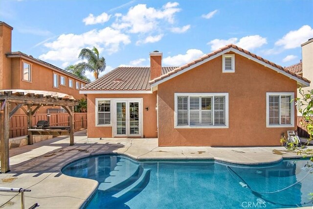 rear view of property with a fenced in pool, a pergola, and a patio area