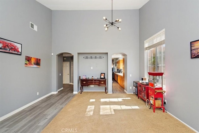 interior space with light hardwood / wood-style flooring, a high ceiling, and an inviting chandelier