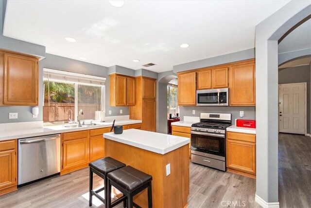 kitchen featuring a breakfast bar, a center island, sink, light hardwood / wood-style flooring, and stainless steel appliances