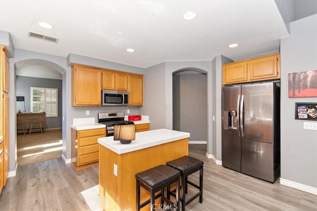 kitchen featuring a breakfast bar area, a center island, stainless steel appliances, and light wood-type flooring