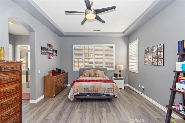 bedroom with light wood-type flooring, multiple windows, and ceiling fan