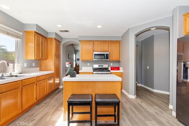 kitchen featuring sink, stainless steel appliances, light hardwood / wood-style flooring, a breakfast bar, and a kitchen island