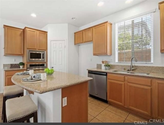 kitchen featuring sink, a center island, stainless steel appliances, a kitchen bar, and light tile patterned flooring