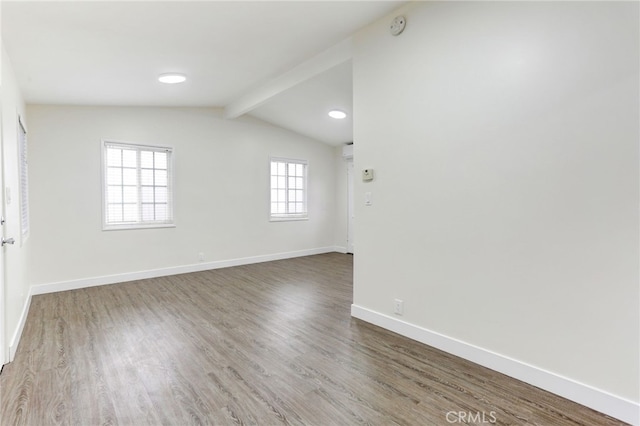 unfurnished room featuring a wealth of natural light, hardwood / wood-style floors, and lofted ceiling with beams