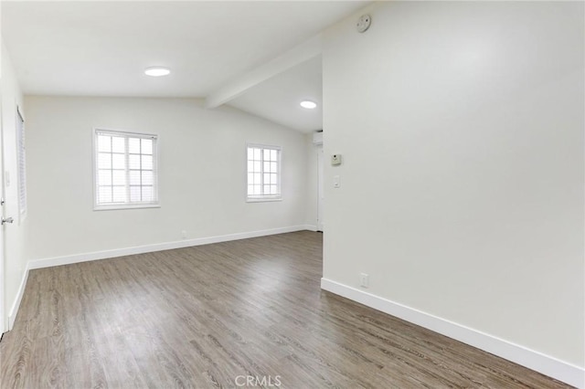 spare room featuring wood finished floors, baseboards, and vaulted ceiling with beams