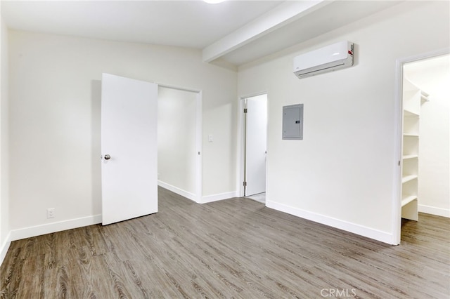 spare room with vaulted ceiling with beams, a wall mounted AC, electric panel, and wood-type flooring