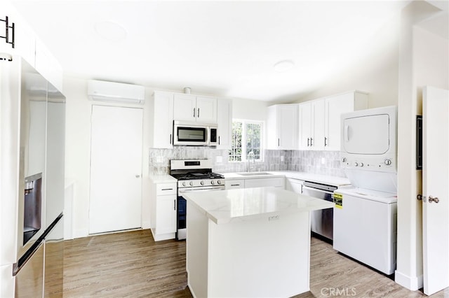 kitchen with appliances with stainless steel finishes, sink, light wood-type flooring, a kitchen island, and white cabinetry