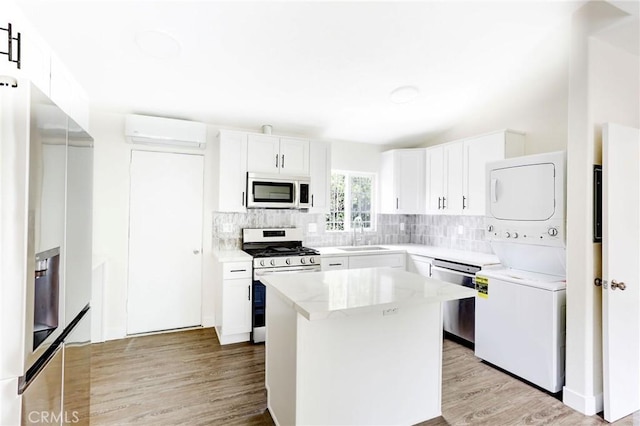kitchen with stacked washer and dryer, a sink, stainless steel appliances, backsplash, and an AC wall unit