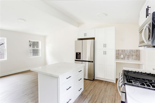 kitchen featuring lofted ceiling with beams, light stone countertops, light wood-type flooring, white cabinetry, and appliances with stainless steel finishes