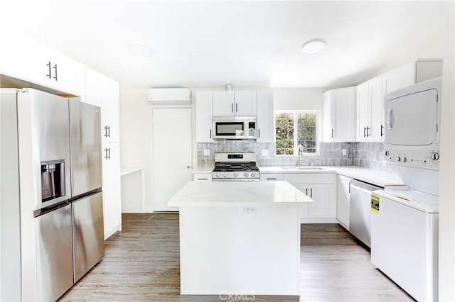 kitchen with stacked washer / dryer, a center island, a sink, stainless steel appliances, and decorative backsplash