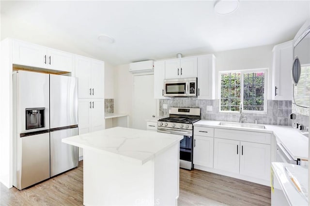 kitchen featuring a sink, stainless steel appliances, tasteful backsplash, an AC wall unit, and a center island