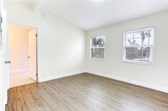 spare room with hardwood / wood-style flooring and vaulted ceiling with beams