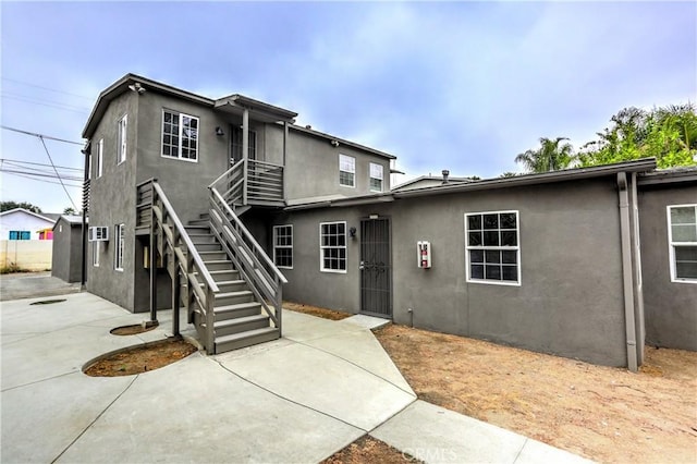 view of front of property with a patio area, stairs, and stucco siding
