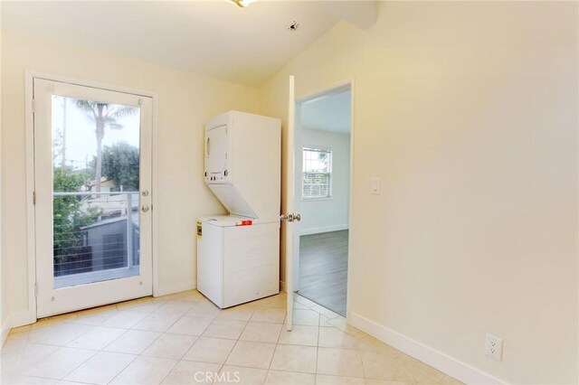 interior space featuring laundry area, light tile patterned flooring, stacked washer / drying machine, and baseboards