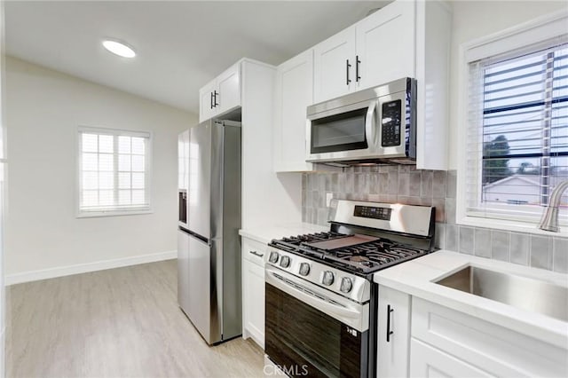 kitchen featuring light countertops, stainless steel appliances, light wood-style flooring, and a sink