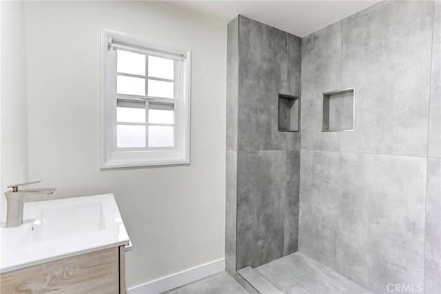 bathroom featuring baseboards, vanity, and tiled shower