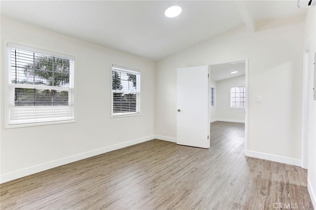 unfurnished room featuring lofted ceiling with beams, light wood-type flooring, and baseboards